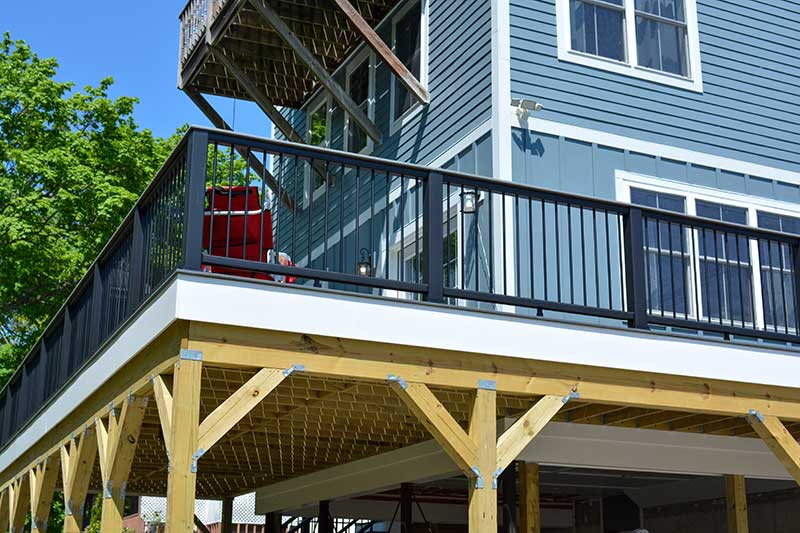 deck_install_inset Angled shot of newly constructed home with wraparound porch, siding, windows, and more.
