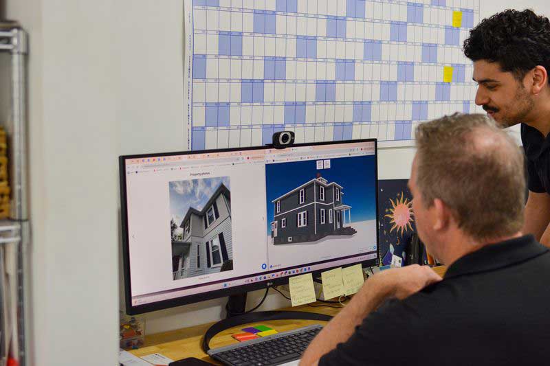gaf_inset Patriot Contracting staff working on a desktop computer with a 3D model of a house.