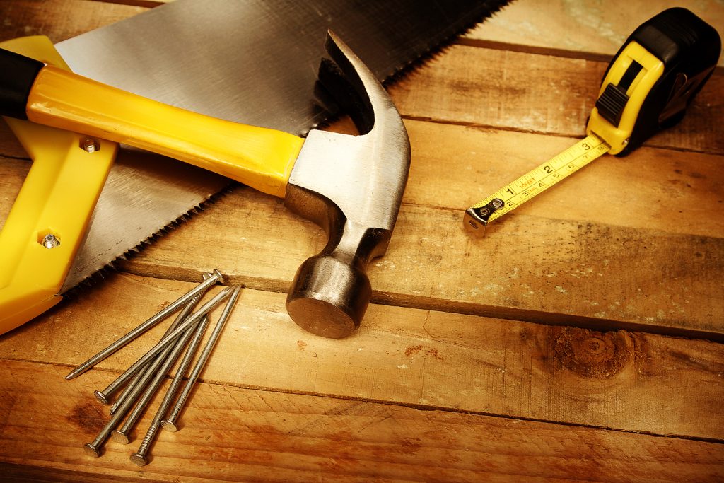 Saw, hammer, nails, and measuring tape as part of a home DIY project.